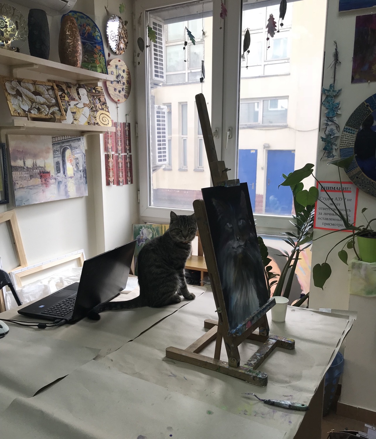 Cat Herman posing beside his portrait by Marina Stognieva while the painting was still in progress